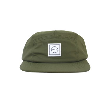 A green nylon five-panel hat with an adjustable velcro back and fabric eyelets on the side panels, featuring a white square logo with a symbol in the center.